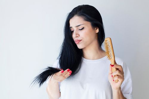 אישה מתוסכלת וחושבת על איך לשקם שיער שבור